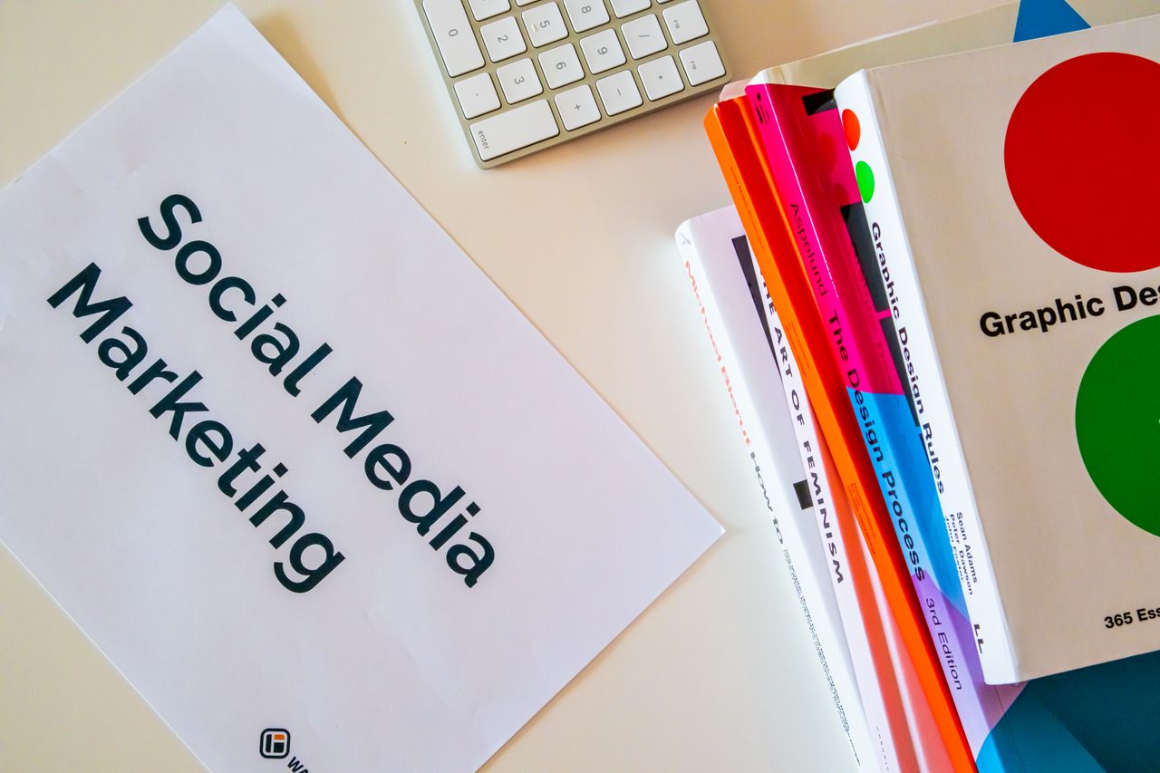 Mastering the First Impression: Your intriguing post title goes here A top view of social media marketing text alongside graphic design books and a keyboard.