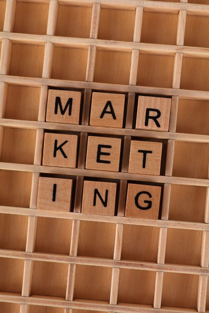 services-02 Wooden letter tiles arranged to spell 'marketing' on a wooden grid, depicting business strategy.
